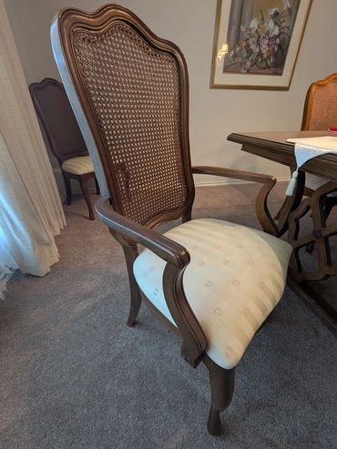 Elegant wooden dining chair with woven back and cushioned seat.