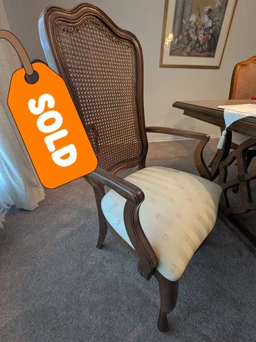 Elegant wooden dining chair with woven back and cushioned seat.