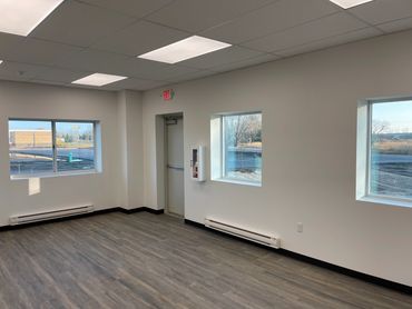 Empty room with windows, wood flooring, and an exit door.