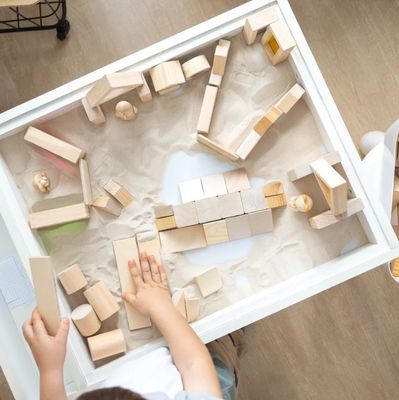 Child playing with wooden blocks in a sand table.
