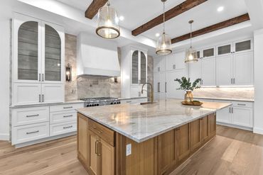 Custom kitchen with a wood island, marble countertop and pendant lighting