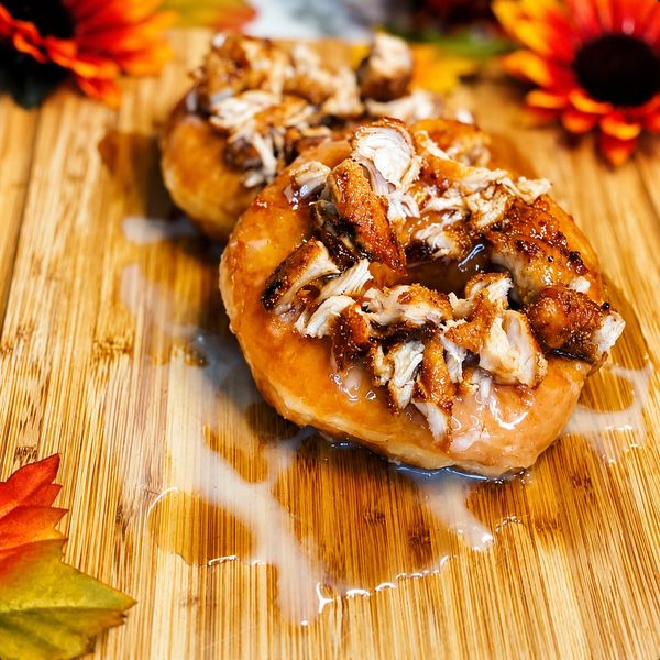 Glazed donuts topped with grilled chicken pieces on a wooden board.