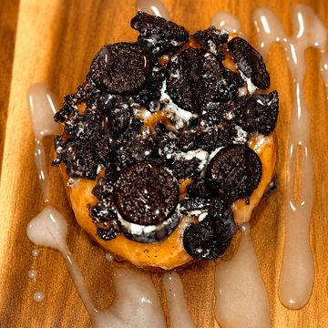 Donut topped with crushed Oreos and icing drizzle.