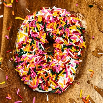 Colorful sprinkled donut on wooden surface.