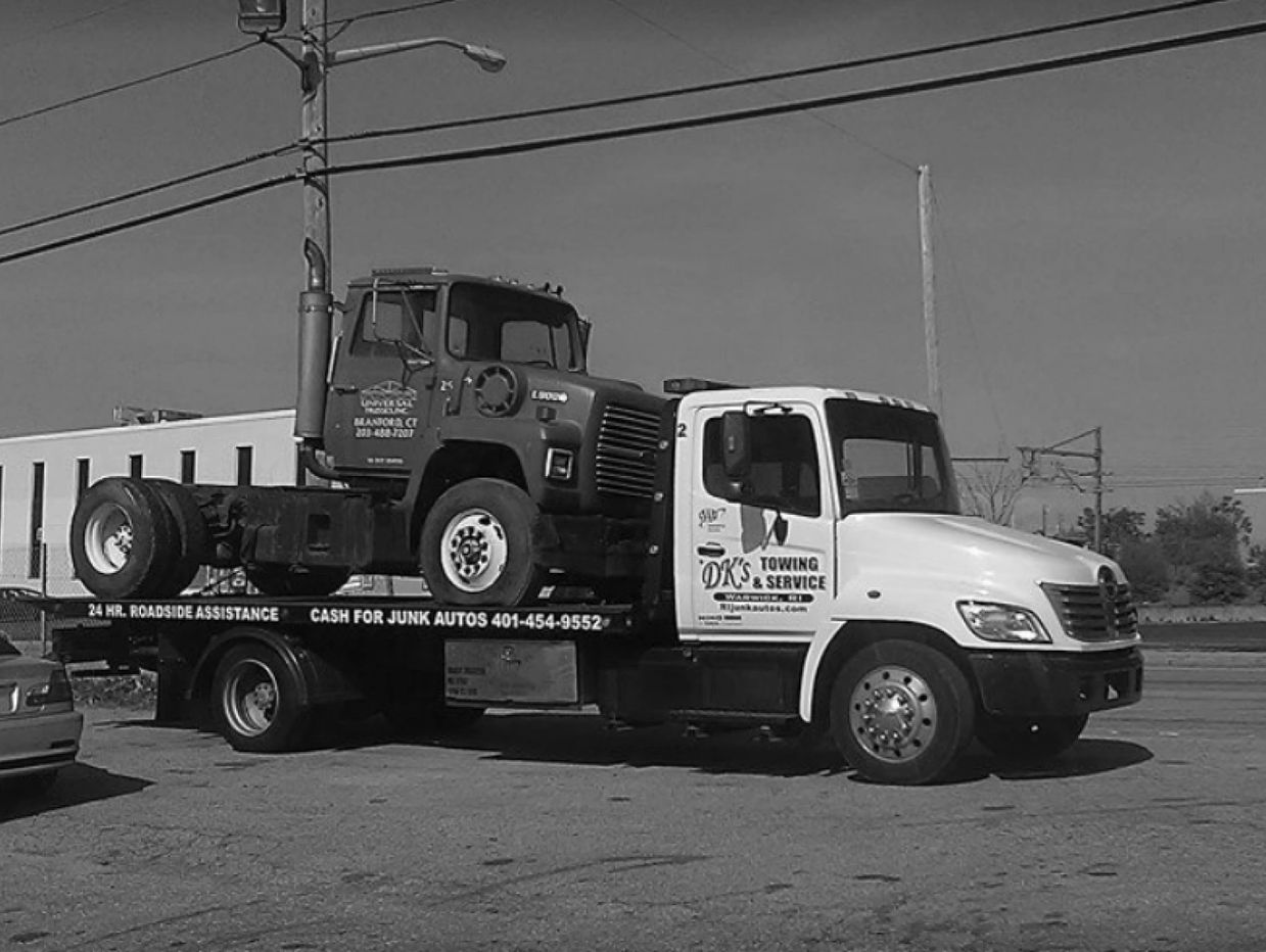 Flatbed Wrecker Service Towing Heavy Equipment to Junkyard
