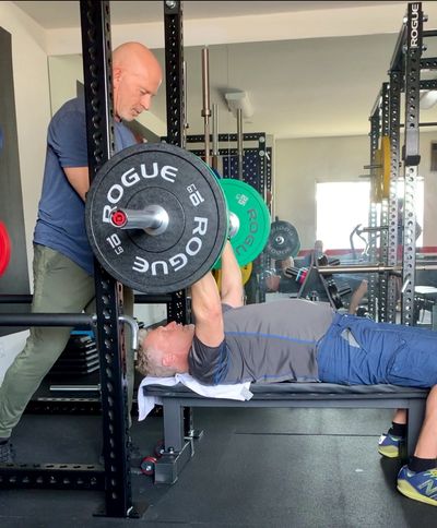 Personal trainer Rudy Mettia coaching a client on bench press.