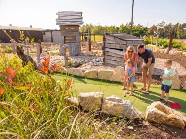 Family playing mini golf on a sunny day at Stonebridge Adventure Golf course near Birmingham West Midlands