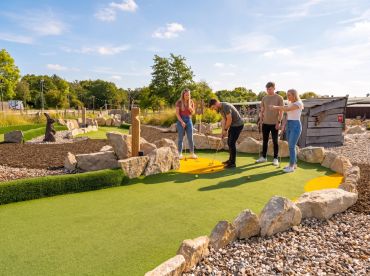Group playing mini golf on a sunny day. Stonebridge Adventure Golf course near Birmingham West Midlands