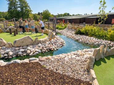 Four friends playing mini golf on a sunny day. Stonebridge Adventure Golf course near Birmingham West Midlands