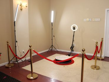 Photo booth setup with red ropes and ring lights in a corner.