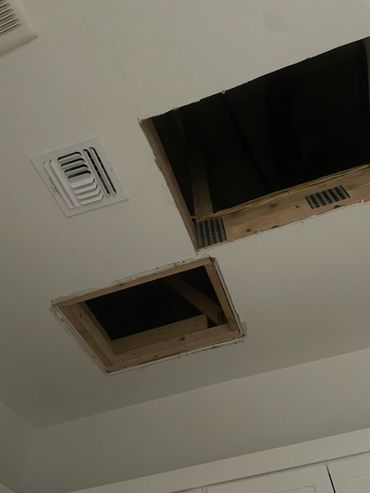 Ceiling with two open attic access holes and a ventilation vent.