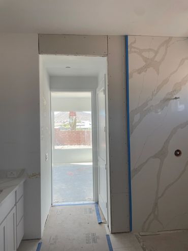 Interior view of a house under construction with drywall and marble wall.