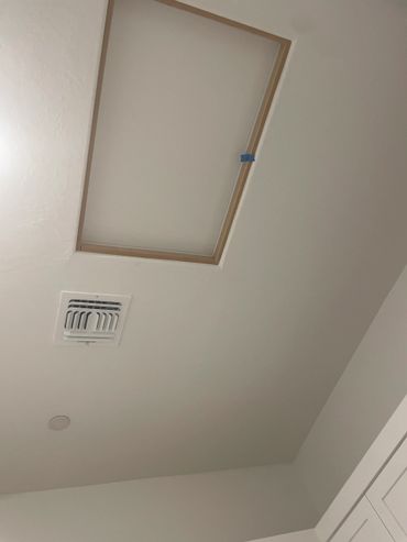 Ceiling with an attic access panel and air vent.