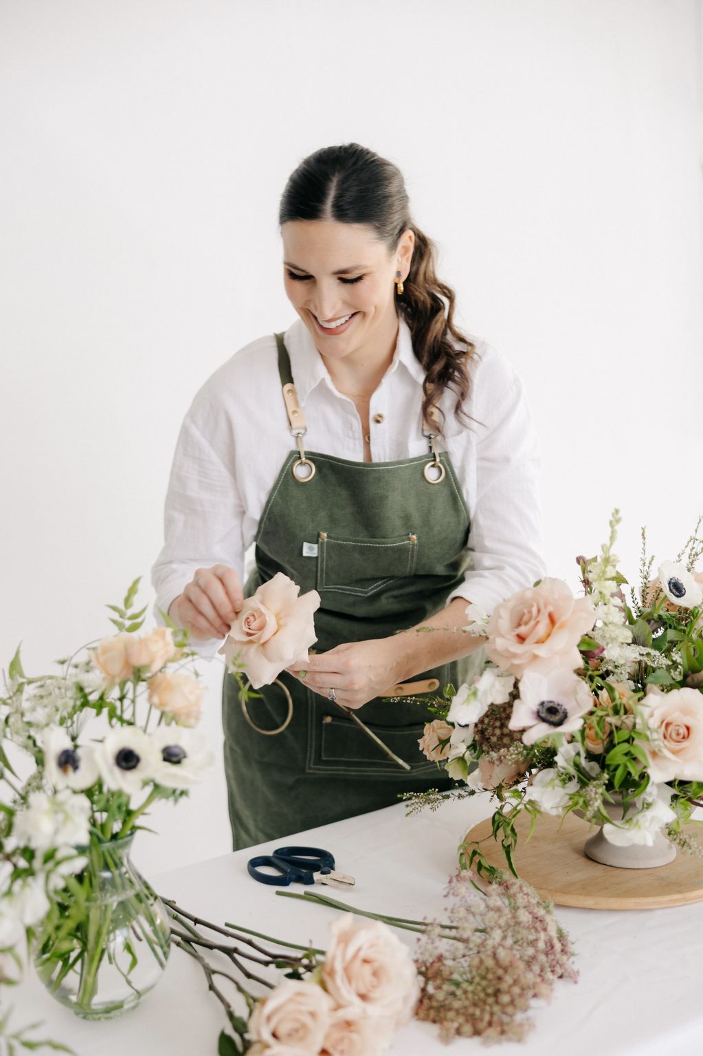 Woman arranging flowers with a smile.