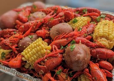A tray of seasoned crawfish with potatoes and corn on the cob.