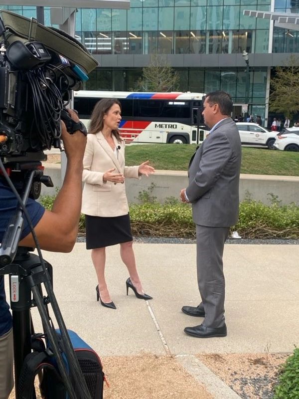 Two people being filmed during an outdoor interview in a city setting.