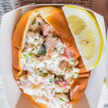 Close-up of a shrimp salad sandwich with a lemon wedge.