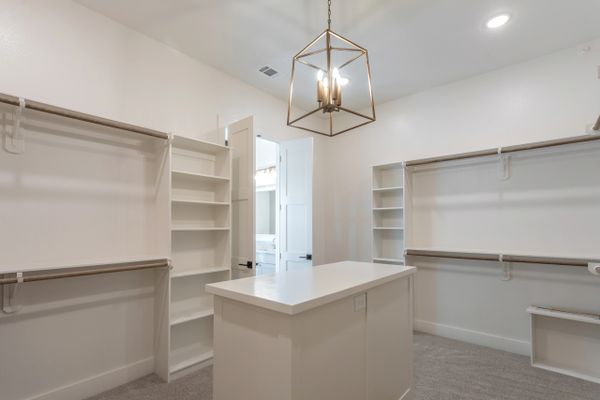 Master closet with chandelier, dresser and shelving