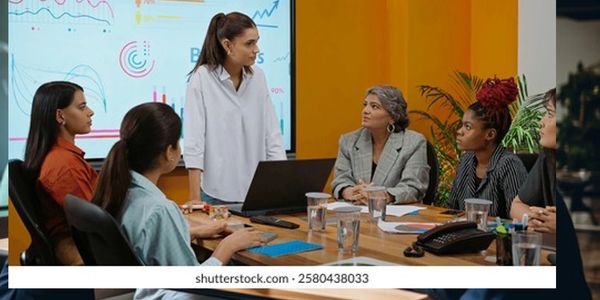 A woman leads a business meeting with attentive colleagues around a table.