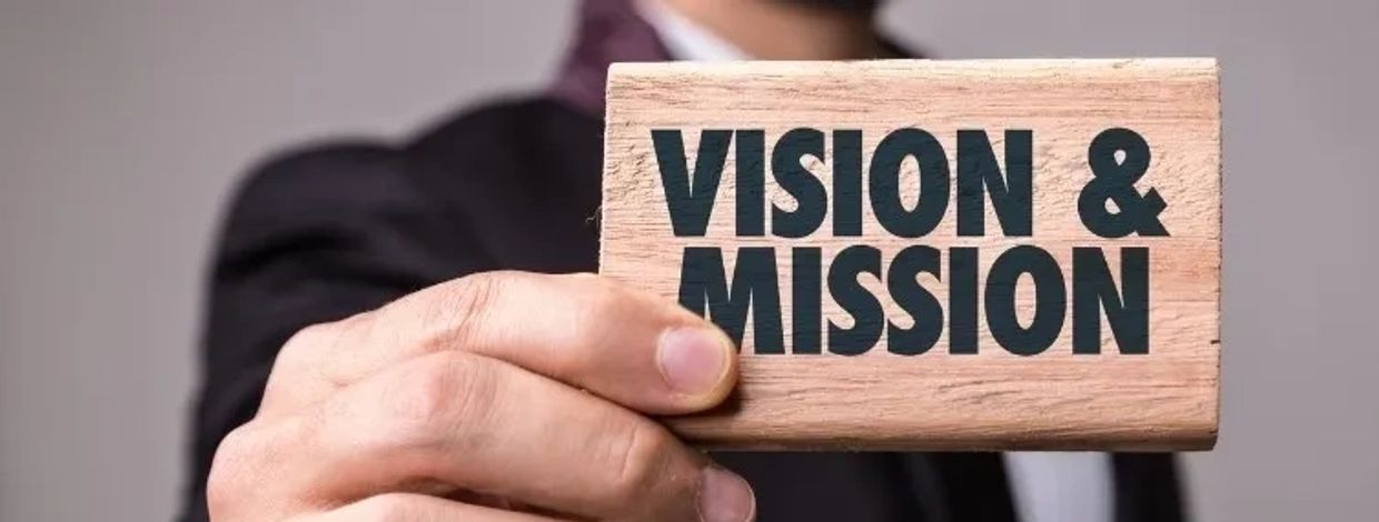 Hand holding a wooden block with 'VISION & MISSION' text.