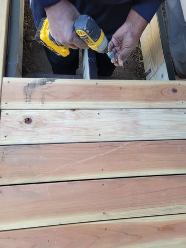Person using a drill to work on wooden planks.