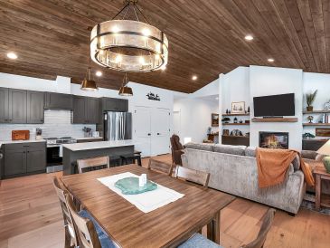 Modern open-concept living area with kitchen and wooden ceiling.