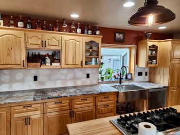 Wood kitchen cabinets, marble countertops, and liquor bottles on top.