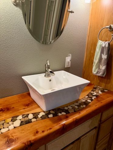 A modern bathroom sink with a wooden countertop and pebble inlay.