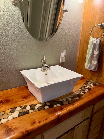 A modern bathroom sink with a wooden countertop and pebble inlay.