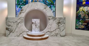 Marble altar with circular niche and stained glass windows in a modern chapel.