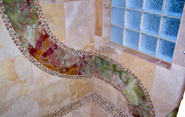 Decorative tiled shower corner with colorful stone inlay and glass blocks.