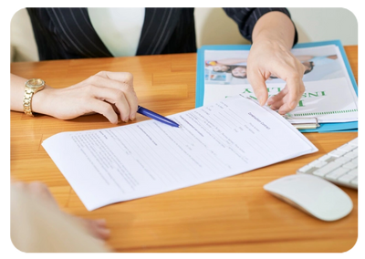 Person pointing to a document on a desk with a pen during a discussion.