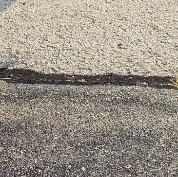 Damaged asphalt crack filled with hot rubber.