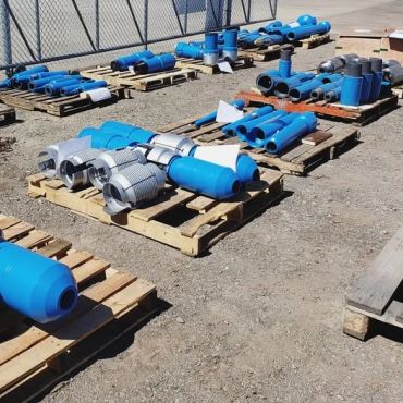 Blue pipes and fittings organized on wooden pallets.