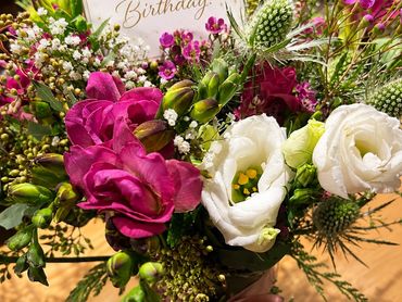 Colorful birthday flower bouquet with card and pink ribbon.