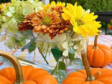 Pumpkins and autumn flowers centerpiece on a table.