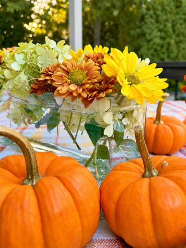 Pumpkins and autumn flowers centerpiece on a table.
