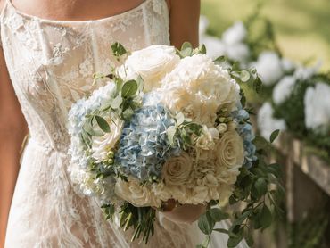 Bride holding a bouquet of white and blue flowers.