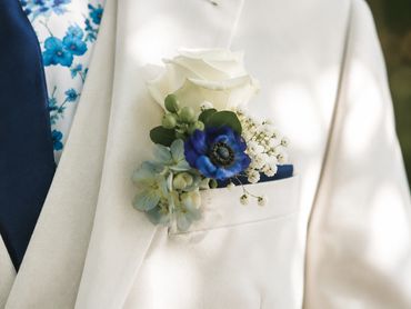 White suit with a floral boutonniere.