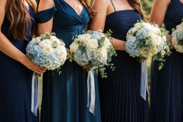 Bridesmaids holding white and blue flower bouquets.