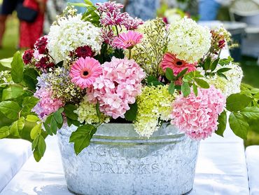 Colorful flower arrangement in a rustic metal bucket.