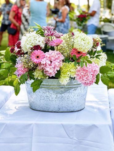 Colorful flower arrangement in a metal bucket on a table.