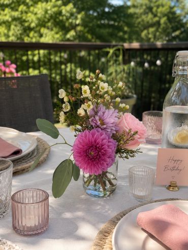 Floral centerpiece on an outdoor birthday table.