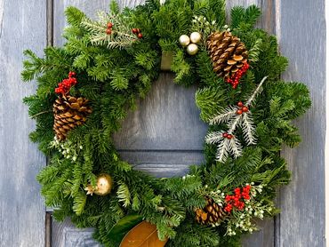 Festive green Christmas wreath with pinecones and red berries.