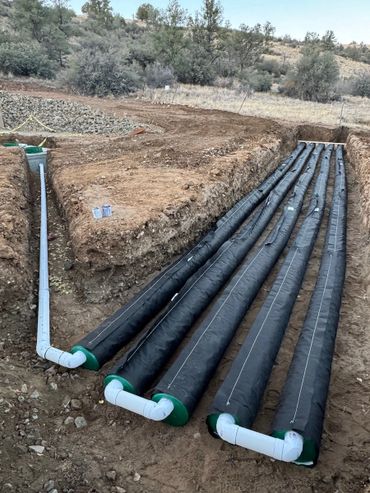 Large black pipes installed in a trench for underground utility or drainage work.