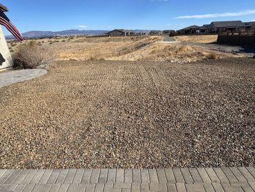 Rock-covered backyard in a desert neighborhood with distant mountains.