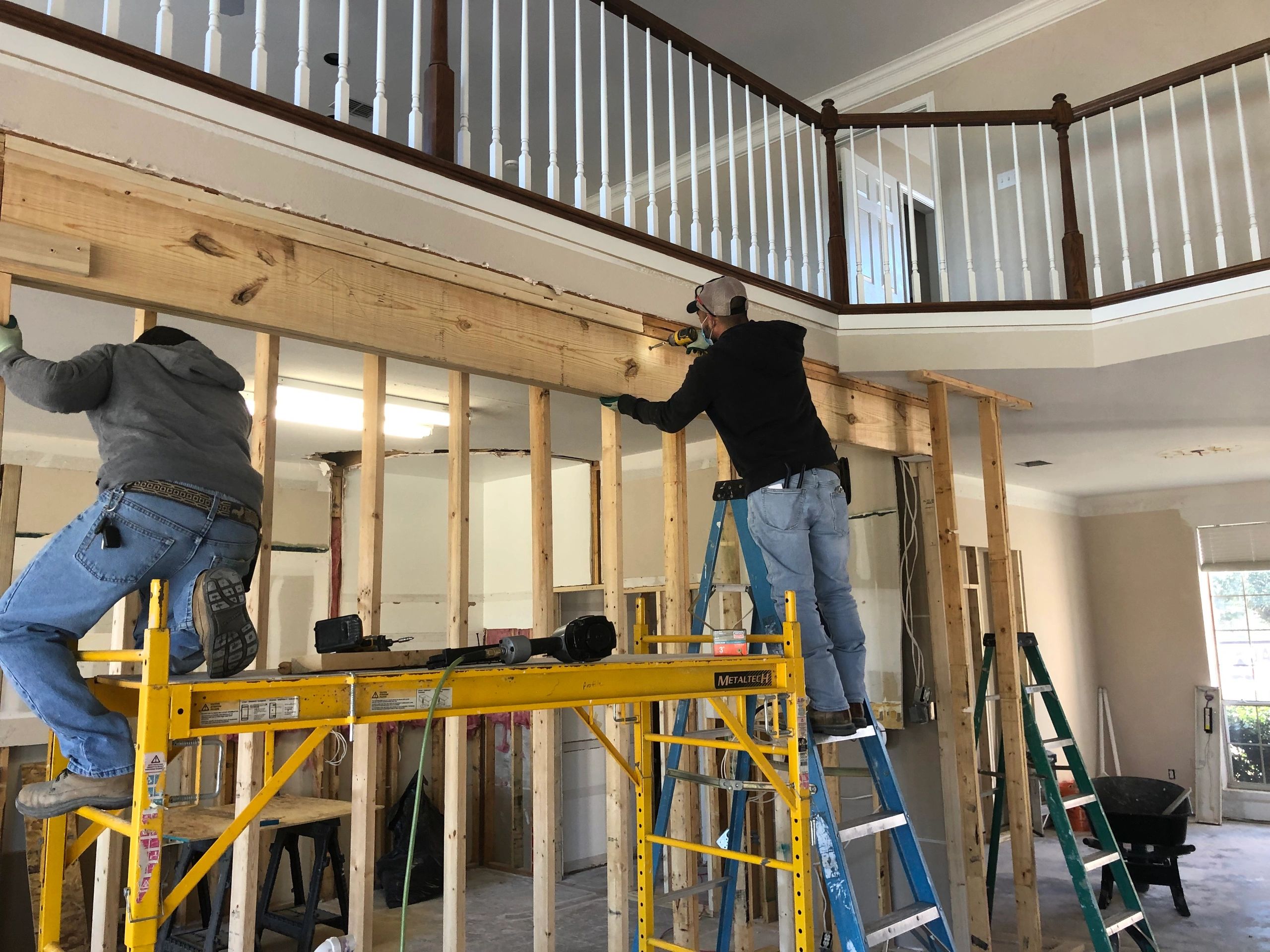 Workers on scaffolding building wall on interior of house.