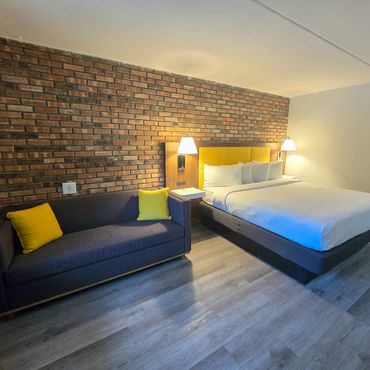 Cozy hotel room with brick wall, yellow accents, and modern furnishings.
