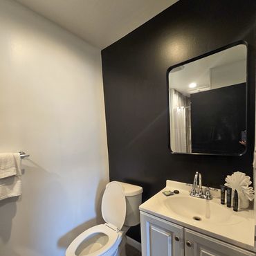 Modern bathroom with black accent wall and white fixtures.