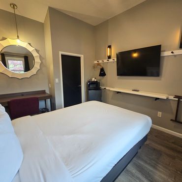 Modern hotel room with a large bed, TV, and stylish decor.